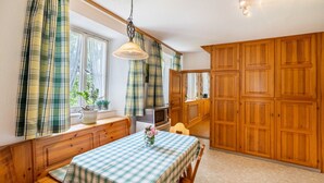 A cozy kitchen with wooden cabinets, a dining table with a checkered tablecloth, and a hanging light fixture. - Apartment 'Fichte' with Shared Terrace, Shared Garden and Wi-Fi (Sankt Georgen im Schwarzwald)