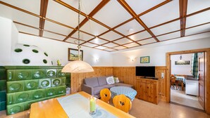 A cozy room with a wooden ceiling, a green cushioned bench, a sofa, a dining table with a candle, and a television. - Apartment 'Fichte' with Shared Terrace, Shared Garden and Wi-Fi (Sankt Georgen im Schwarzwald)