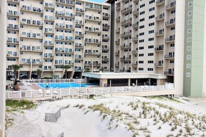 Ein Hochhaus-Hotel mit mehreren Balkonen, einem Schwimmbad und einer überdachten Außenanlage.
