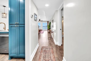 Ein Flur mit einem blauen Schrank, einem Teppich und Blick auf einen Balkon.