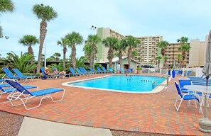 A pool area with blue lounge chairs and palm trees. - Pinnacle Port C3-701 (Panama City Beach)