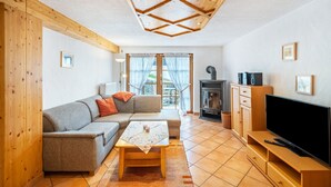 A living room with a sofa, a coffee table, a TV, wooden cabinets, and a fireplace. - Apartment 'Buche' with Shared Terrace, Shared Garden and Wi-Fi (Sankt Georgen im Schwarzwald)