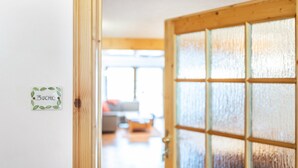 A wooden door with frosted glass panels, a sign on the wall, and a glimpse of a living room in the background. - Apartment 'Buche' with Shared Terrace, Shared Garden and Wi-Fi (Sankt Georgen im Schwarzwald)