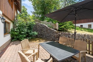 An outdoor patio with wicker furniture, a table, and an umbrella. - Apartment 'Buche' with Shared Terrace, Shared Garden and Wi-Fi (Sankt Georgen im Schwarzwald)