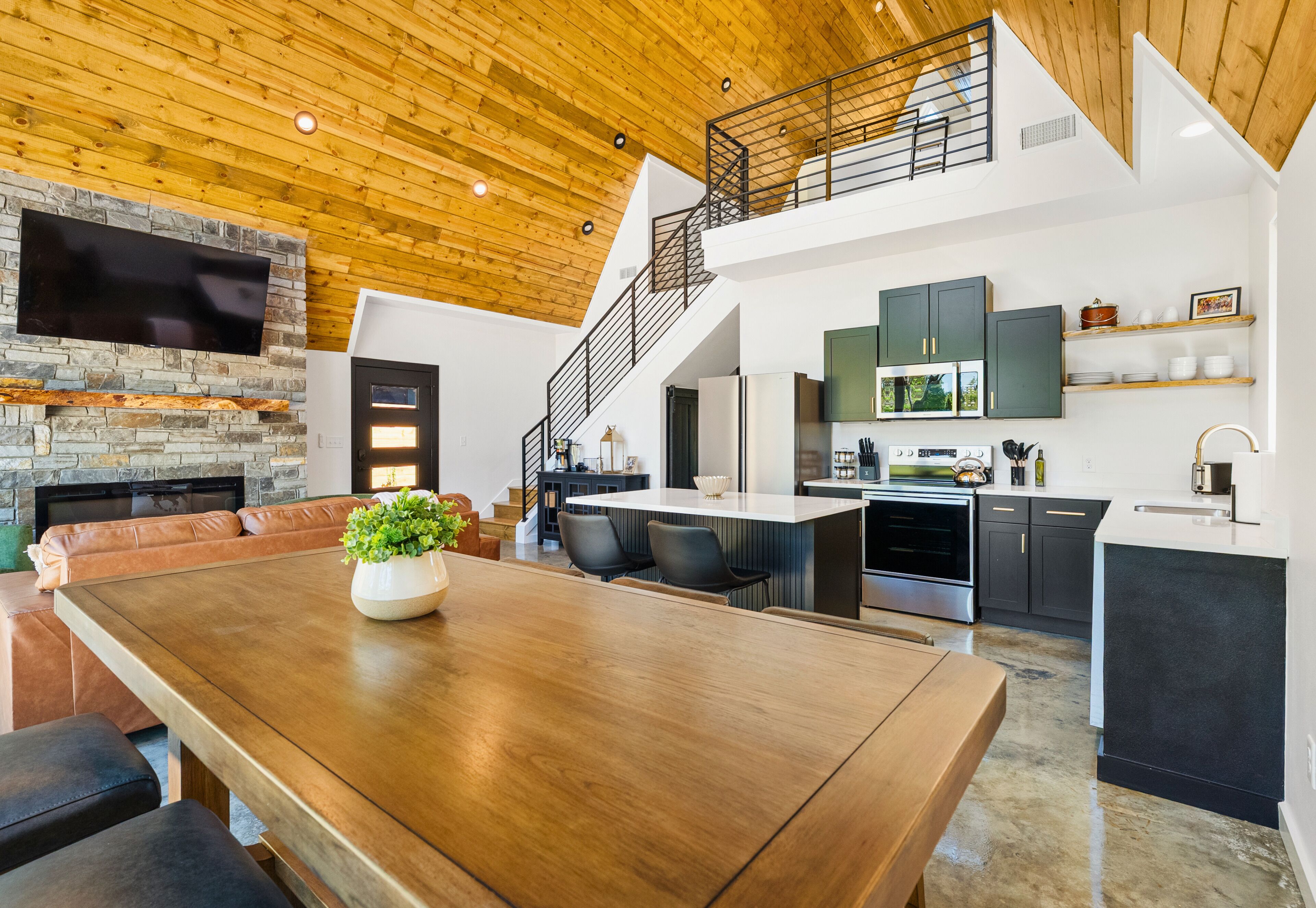 Una cocina moderna con una isla central, un comedor con mesa de madera y una sala de estar con chimenea.