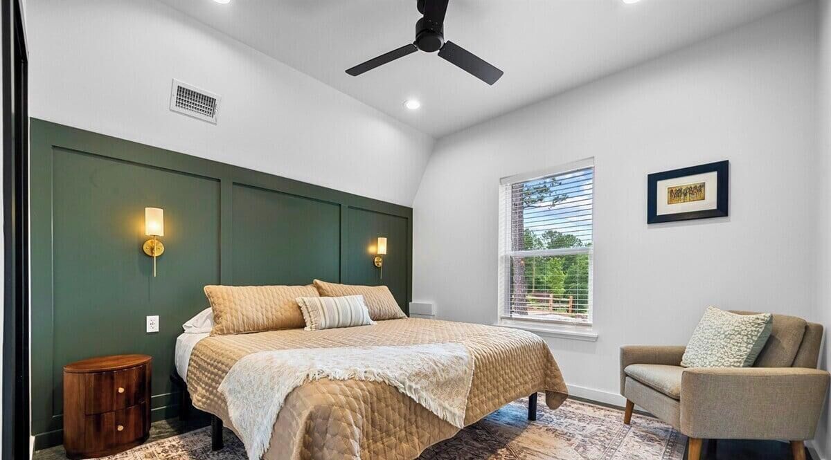 A bedroom with a bed, a chair, a window, and a ceiling fan.