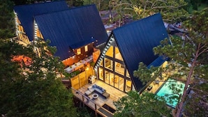 A modern cabin with a large deck, a swimming pool, and a well-lit interior. - New Modern Cabin with Pool, Sauna, and Cold Plunge (Garland County)
