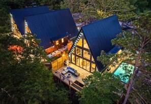 A modern cabin with a large deck, a swimming pool, and a well-lit interior. - New Modern Cabin with Pool, Sauna, and Cold Plunge (Garland County)