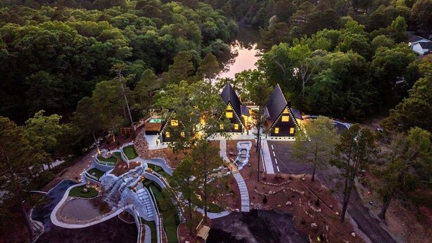 A resort with multiple buildings, a winding pathway, and a body of water. - New Modern Cabin with Pool, Sauna, and Cold Plunge (Garland County)