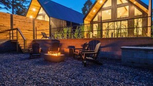 A cabin with a fire pit, outdoor seating, and large windows. - Stylish A-Frame Getaway with Pool and Lake Access (Garland County)