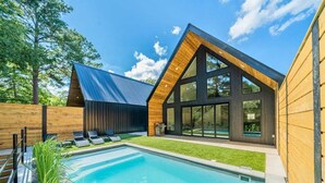 A modern house with a swimming pool, large windows, and a sloped roof. - Stylish A-Frame Getaway with Pool and Lake Access (Garland County)