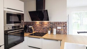 A kitchen with a brick backsplash, a microwave, an oven, a coffee maker, and a window. - 19th-century farmhouse between Troyes and Provins (Soligny-les-Étangs)