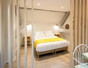 Ein Schlafzimmer mit einem Bett, Nachttischen, Holzboden und schrägen Wänden.
