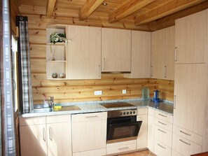 Eine Küche mit Holzausstattung, einem Herd und einem Fenster mit Vorhängen.