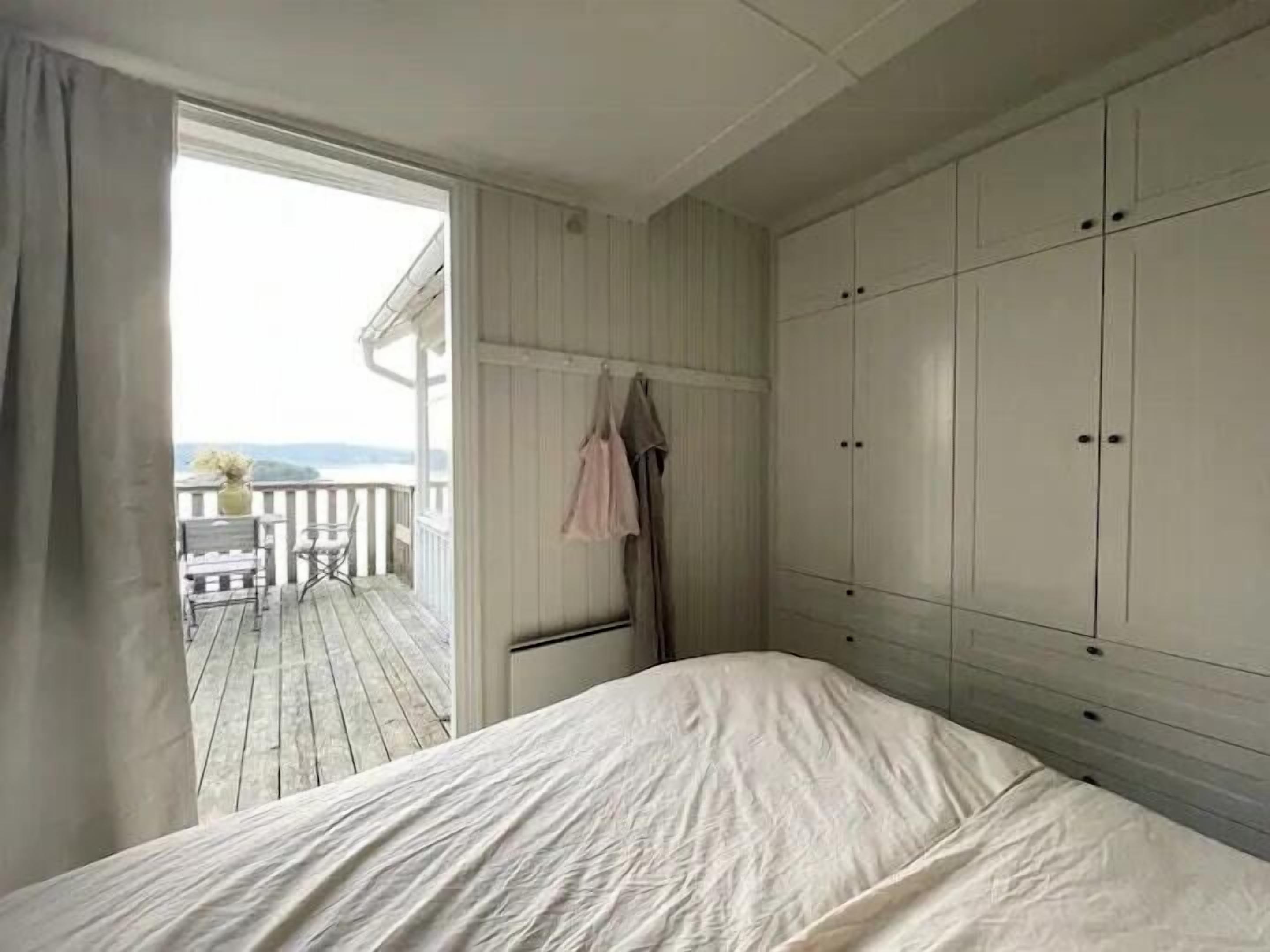 A bedroom with a bed, a wardrobe, and a balcony with a table and chairs.