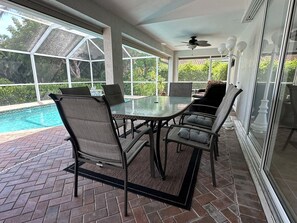 Un patio cubierto con piscina, mobiliario exterior y grandes ventanales que ofrecen vistas al exterior.
