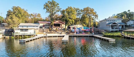 A waterfront property with a dock, a covered area, and a house with a large deck.