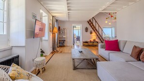 A spacious living room with a sofa, a coffee table, and a staircase leading to an upper floor. - GuestReady - Casa do Horizonte (Mosteiros)