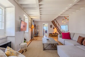 A spacious living room with a sofa, a coffee table, and a staircase leading to an upper floor.