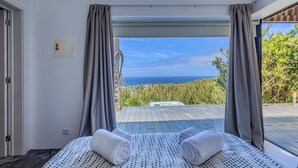 A room with a bed, towels, and a view of the ocean. - GuestReady - Casa do Horizonte (Mosteiros)