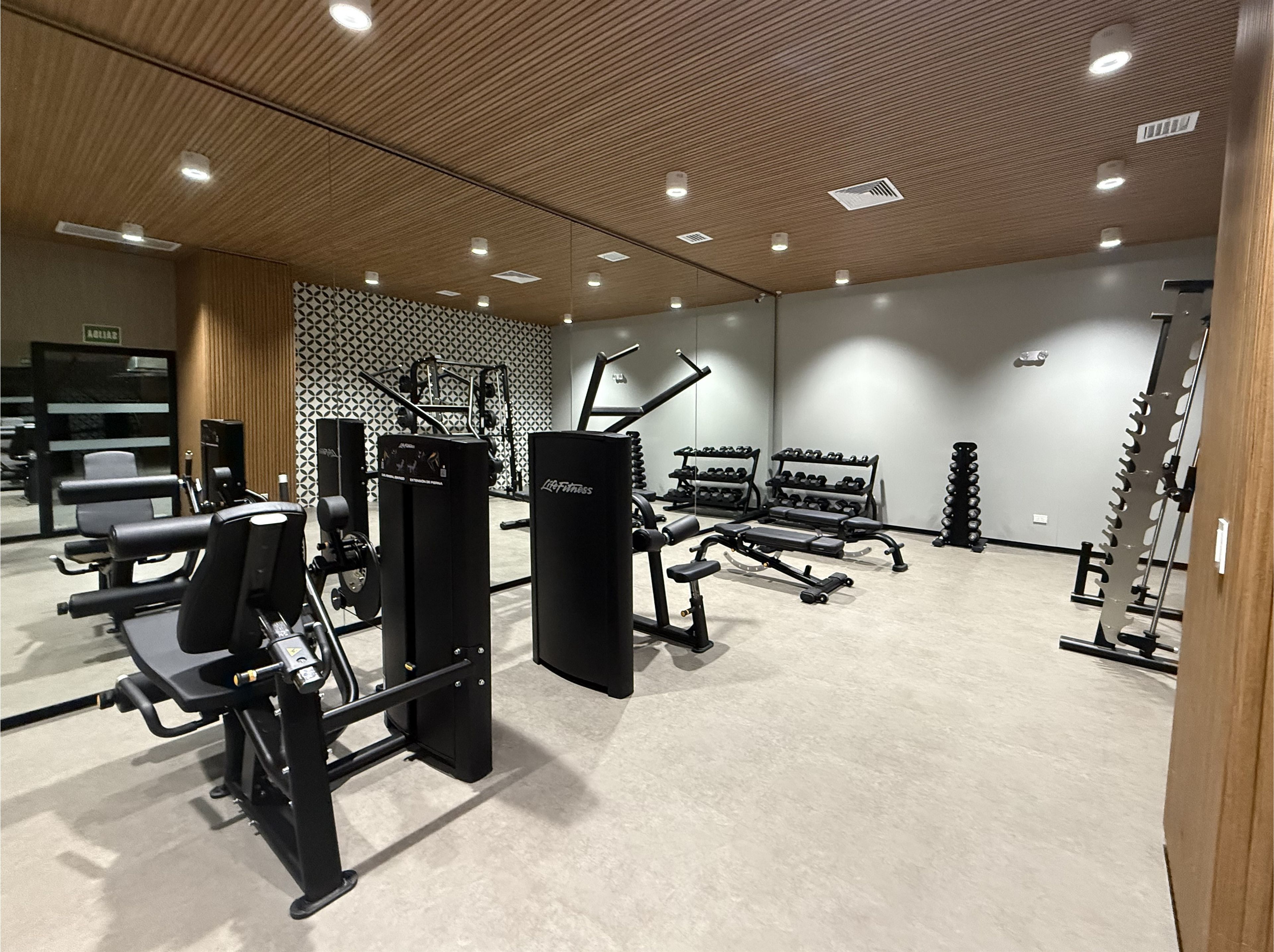 Une salle de sport équipée de divers appareils d’entraînement, notamment des machines à poids et des poids libres.