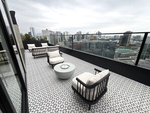 A rooftop terrace with a geometric tile floor, modern outdoor furniture, and a cityscape view.