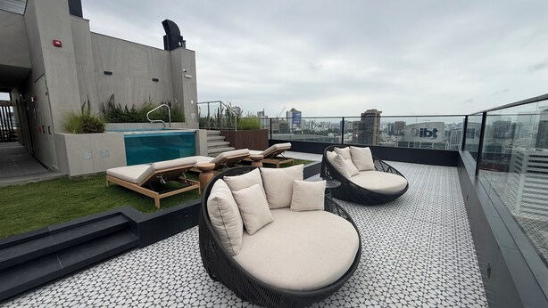 Une terrasse sur le toit avec une piscine, des chaises longues et une vue sur la ville.