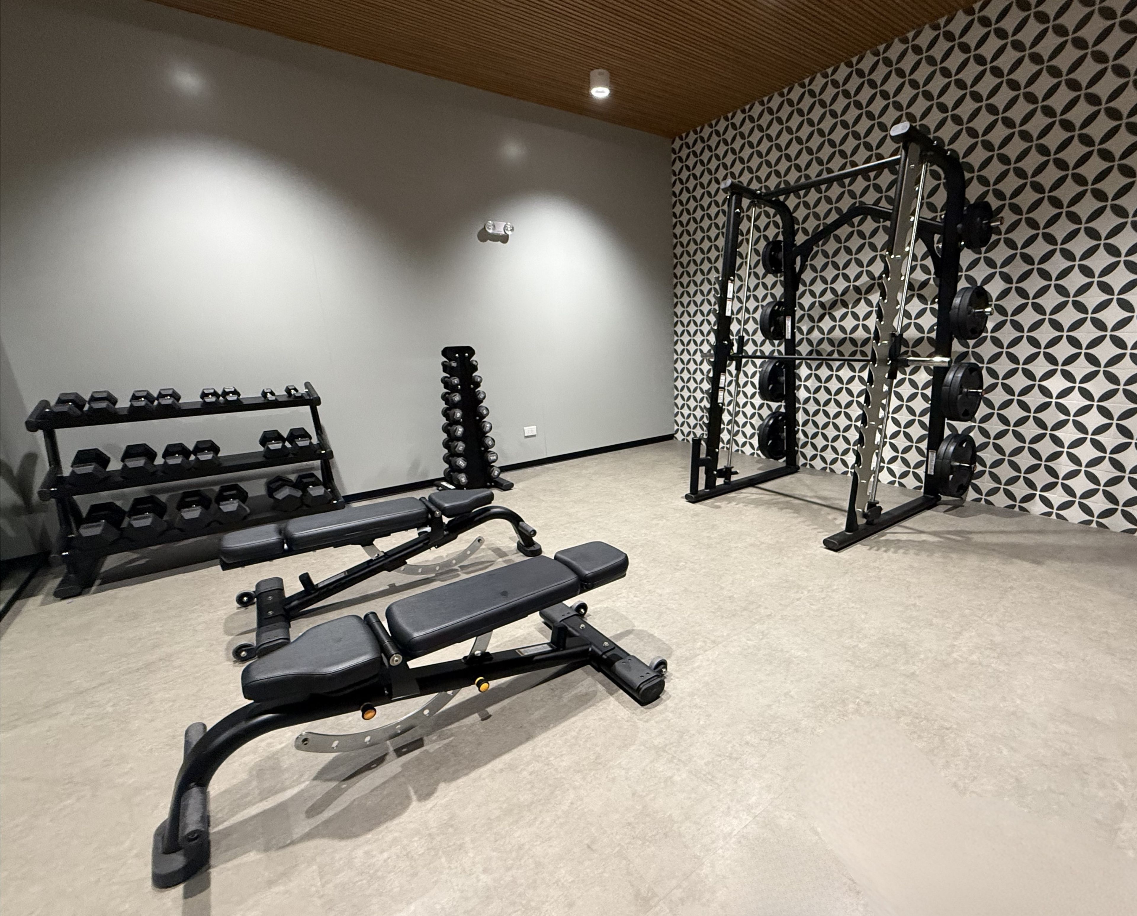 A gym with a bench press, dumbbells, and a squat rack.