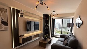 Un salon moderne avec un téléviseur à écran plat, un canapé, une table basse et une bibliothèque.