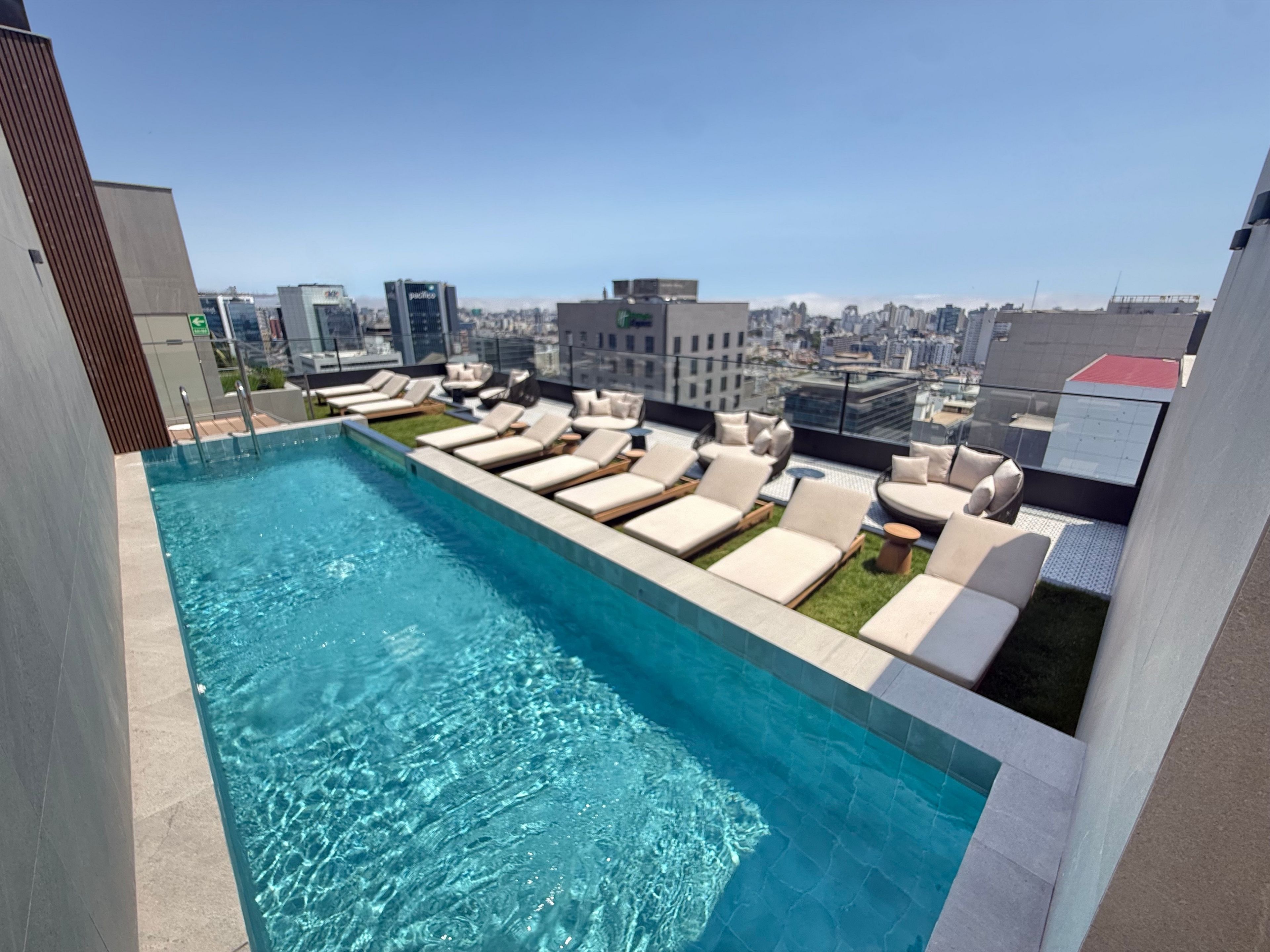 A rooftop pool with lounge chairs and a city view.