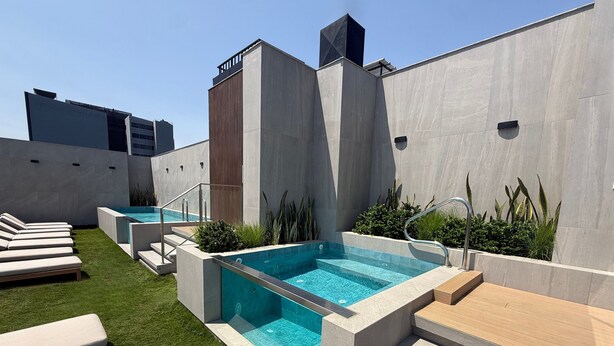 A rooftop pool area with a clear blue pool, sun loungers, and a wooden deck. - Aparts4Days 1 Bedroom Apartment AR (Lima)