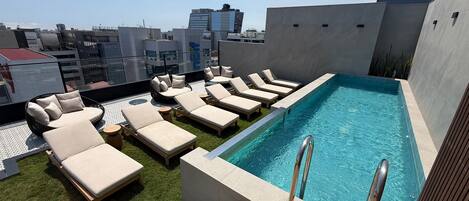 A rooftop pool area with lounge chairs and a swimming pool.