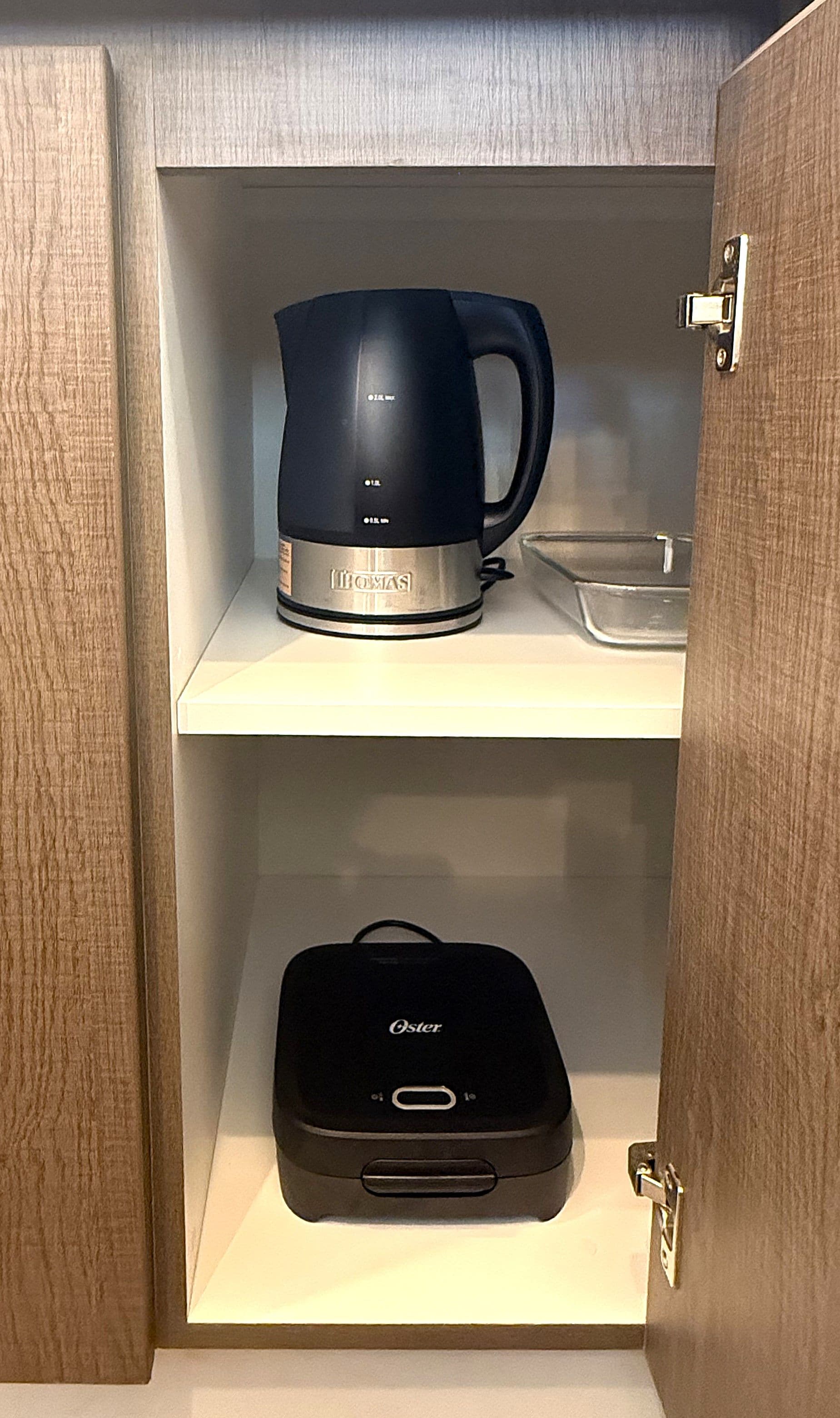 Een koffiezetapparaat en een draagbare oplader op een plank.