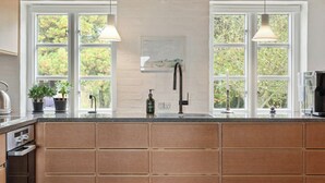 A kitchen with wooden cabinets, a large island, a sink, and pendant lights.