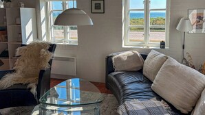 A living room with a glass table, leather sofa, and a dog.