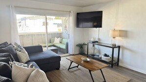 Een moderne woonkamer met een bank, salontafel en een televisie aan de muur.