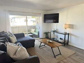 Una sala de estar moderna con un sofá, una mesa de centro y un televisor montado en la pared.
