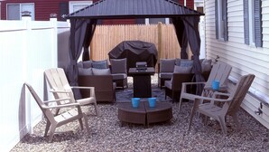 An outdoor patio with a covered seating area, a grill, and a view of a residential neighborhood. - Spacious 5-bedroom WAVES OF HAMPTON I & II Combined (Hampton)