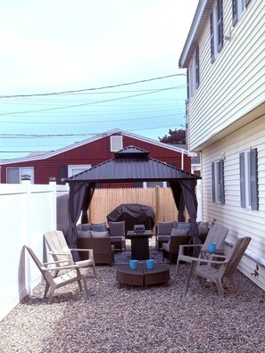 An outdoor patio with a covered seating area, a grill, and a view of a residential neighborhood. - Spacious 5-bedroom WAVES OF HAMPTON I & II Combined (Hampton)