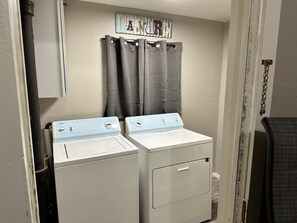 A laundry area with two front-loading washers and a metal sign above them.