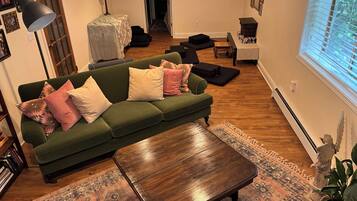 Un canapé vert avec des coussins, une table basse en bois, un tapis à motifs, une lampe et une statue.