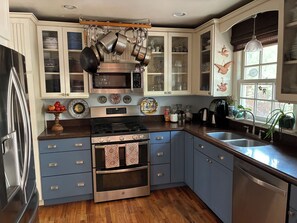 Une cuisine équipée d’une cuisinière, d’un four, d’un four à micro-ondes et de casseroles suspendues.