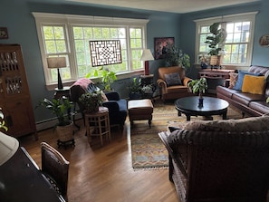Un salon chaleureux avec une cheminée, des fauteuils confortables et de grandes fenêtres.