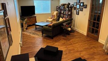 A living room with a sofa, a coffee table, a bookshelf, and a television.