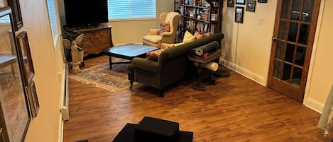 A living room with a sofa, a coffee table, a bookshelf, and a television.