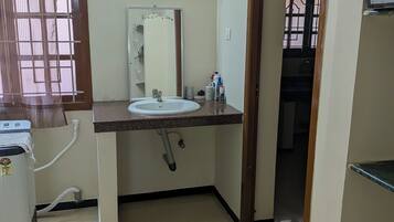 Casa de banho com lavatório, espelho, porta-toalhas e janela com cortina.