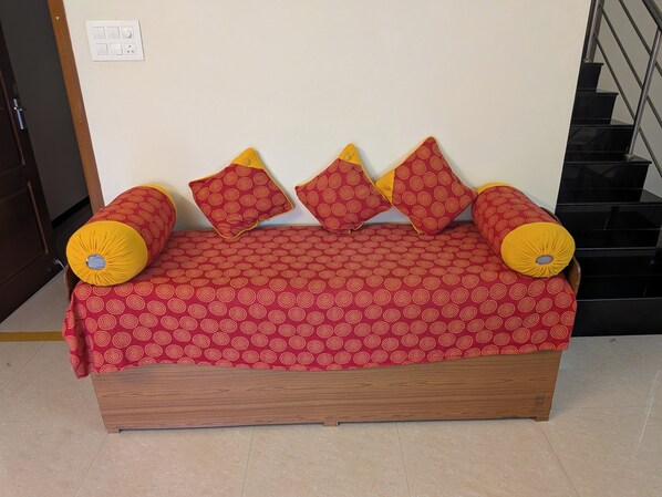 A bed with a patterned cover, wooden frame, and two yellow pillows.