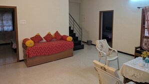 Ein Wohnzimmer mit einer Couch, einem Esstisch mit Stühlen, einer Treppe und einer Tür zu einem anderen Raum.