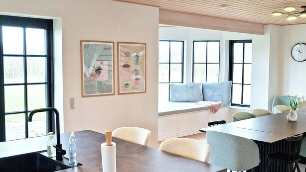 A modern kitchen with a central island, a dining area with chairs, and large windows. - Newly renovated holiday home near HimmerLand (Farsø)
