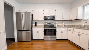 Une cuisine moderne dotée d’appareils électroménagers en acier inoxydable, de meubles blancs et d’un plancher en bois.